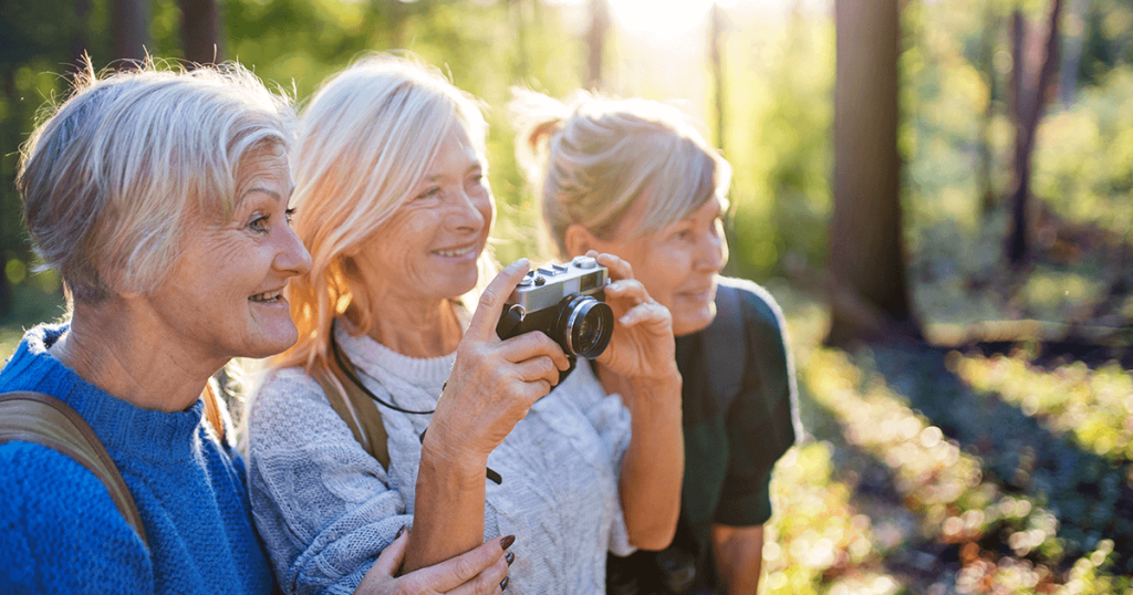 Three women who manage overactive bladder looking out into the distance at nature with a camera