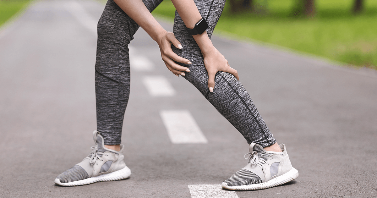 woman in sports leggings soothing her knee after an injury